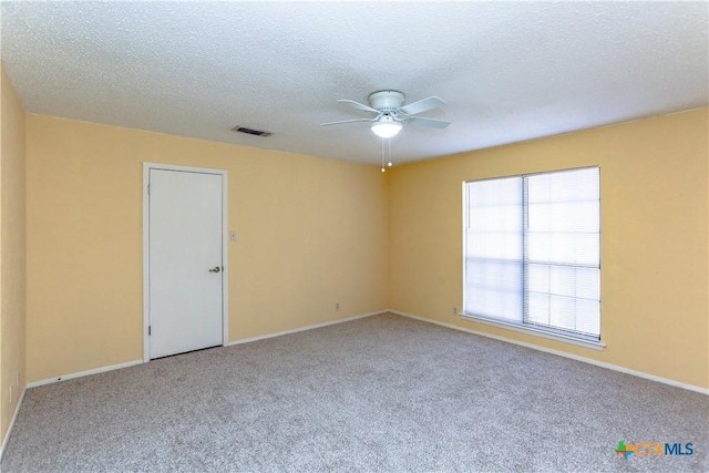 unfurnished room with a textured ceiling, visible vents, and light colored carpet