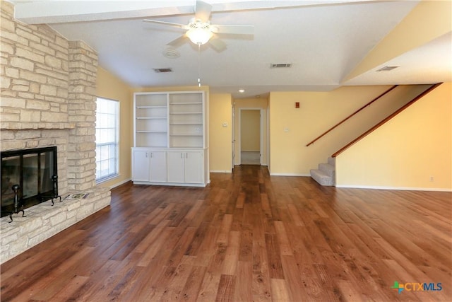 unfurnished living room featuring dark wood-style floors, visible vents, stairway, lofted ceiling with beams, and a stone fireplace