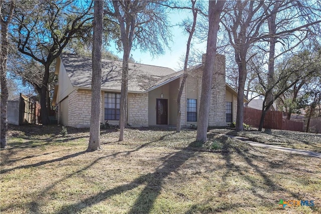 exterior space featuring stone siding, a lawn, and fence