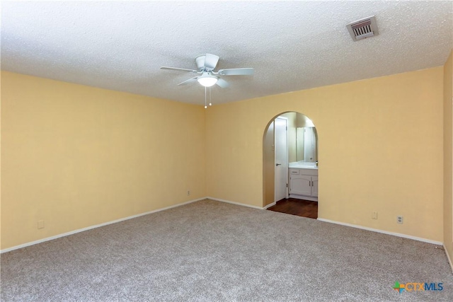 unfurnished room with arched walkways, visible vents, carpet flooring, ceiling fan, and a textured ceiling