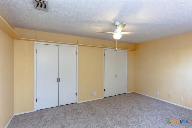 unfurnished bedroom with a ceiling fan, visible vents, a textured ceiling, and light colored carpet