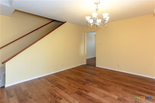 interior space with baseboards, stairway, wood finished floors, an inviting chandelier, and a textured ceiling