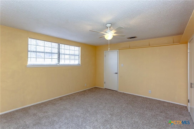 carpeted empty room featuring visible vents, ceiling fan, a textured ceiling, and baseboards