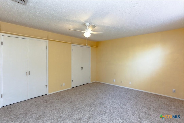 unfurnished bedroom with multiple closets, light colored carpet, ceiling fan, a textured ceiling, and baseboards