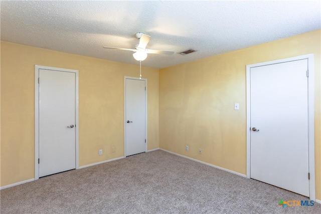 interior space with light carpet, a textured ceiling, visible vents, and a ceiling fan