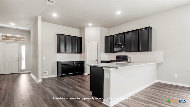 kitchen with a healthy amount of sunlight, decorative backsplash, black appliances, and dark wood-type flooring