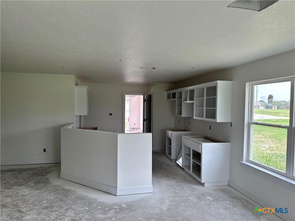 2115 Blackhawk Loop, Belton, TX 76513 - kitchen with open shelves, a textured ceiling, unfinished concrete floors, baseboards, and plenty of natural light