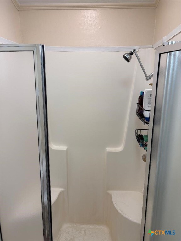 full bath featuring ornamental molding and a stall shower