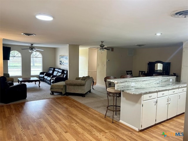 kitchen featuring open floor plan, visible vents, ceiling fan, and light wood finished floors