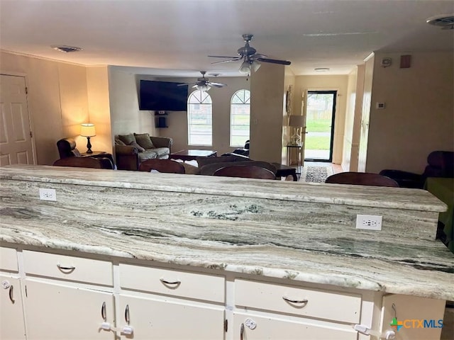 kitchen featuring light countertops, white cabinets, visible vents, and ceiling fan