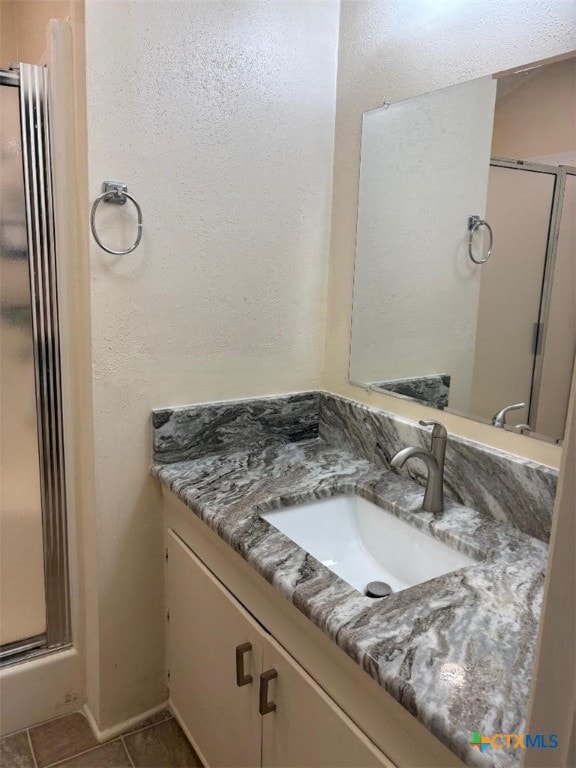 full bathroom featuring a stall shower, vanity, and tile patterned floors