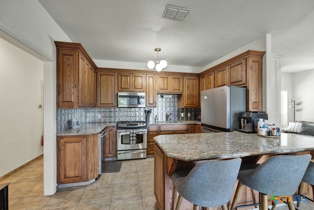 kitchen with stainless steel appliances, sink, kitchen peninsula, tasteful backsplash, and light stone countertops