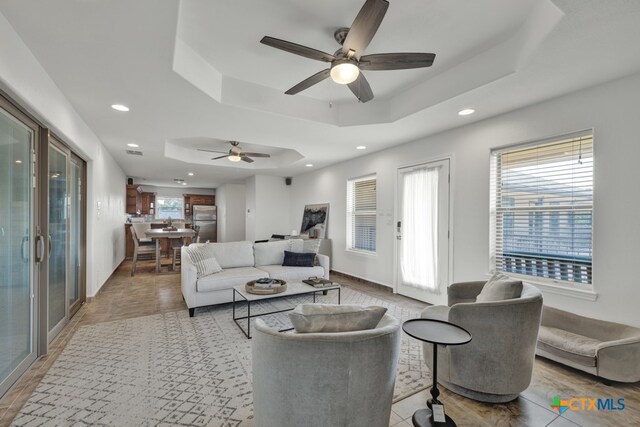 living room with ceiling fan and a raised ceiling