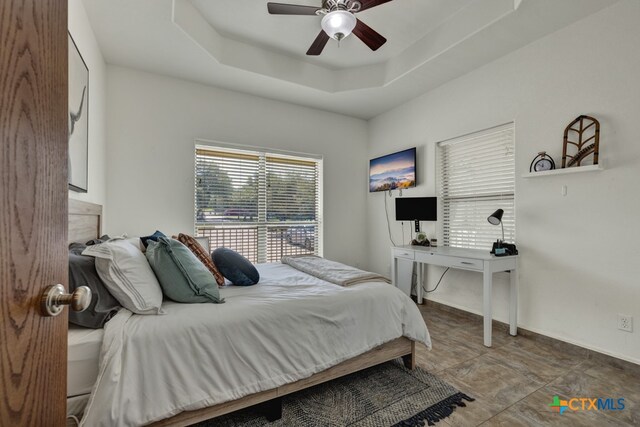 bedroom with ceiling fan and a tray ceiling