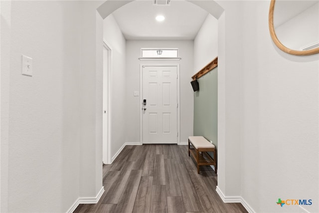 doorway featuring baseboards, visible vents, arched walkways, and dark wood finished floors