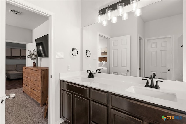 full bathroom with ensuite bathroom, double vanity, a sink, and visible vents