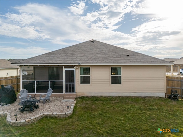 back of property featuring an outdoor fire pit, a shingled roof, fence, a sunroom, and a yard