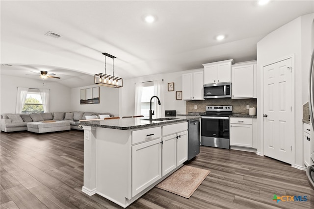 kitchen with stainless steel appliances, visible vents, dark wood-type flooring, a sink, and an island with sink