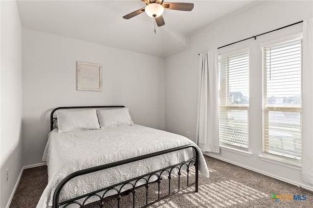 carpeted bedroom with ceiling fan, multiple windows, and baseboards