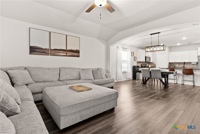 living area with arched walkways, ceiling fan, lofted ceiling, recessed lighting, and dark wood finished floors