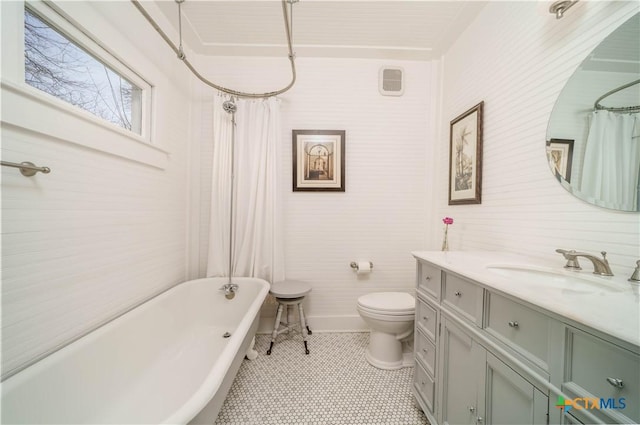 full bathroom featuring a shower with shower curtain, a freestanding bath, vanity, and toilet