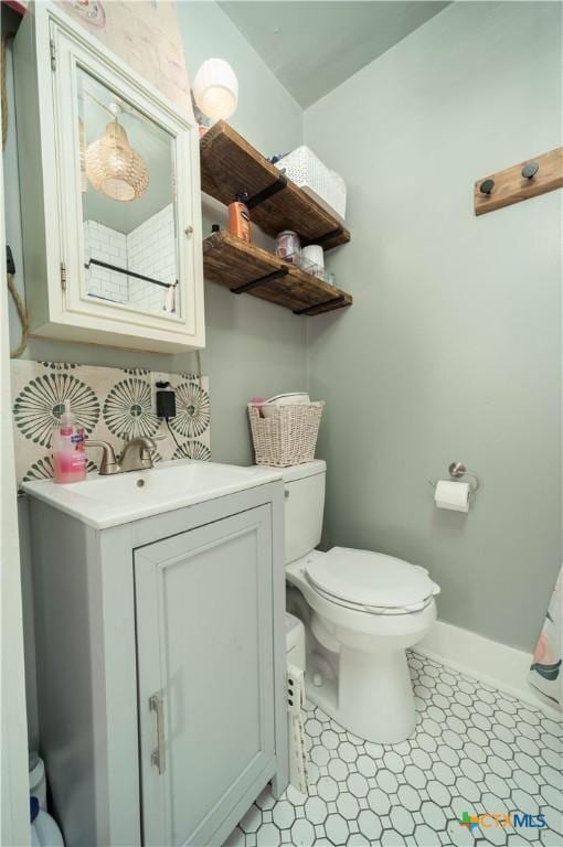 bathroom featuring baseboards, toilet, and vanity