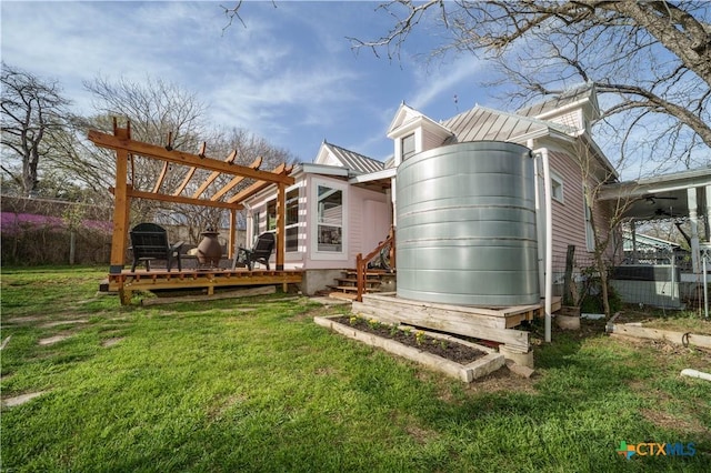 rear view of property with a standing seam roof, a wooden deck, a lawn, and metal roof