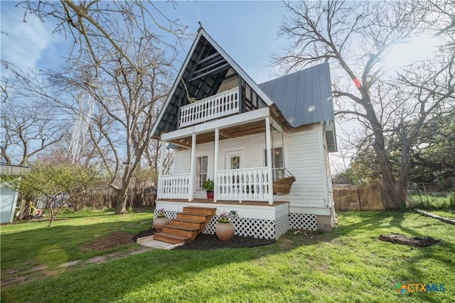 view of front of property featuring a front lawn, fence, covered porch, metal roof, and a balcony