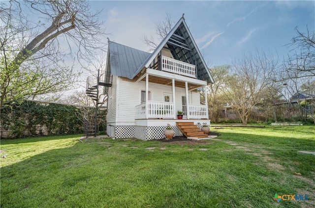 view of front facade featuring a balcony, a porch, metal roof, and a front yard