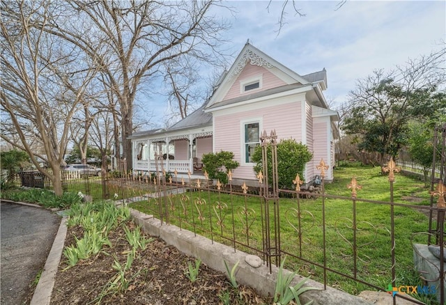 victorian house featuring a fenced front yard, covered porch, and a front lawn