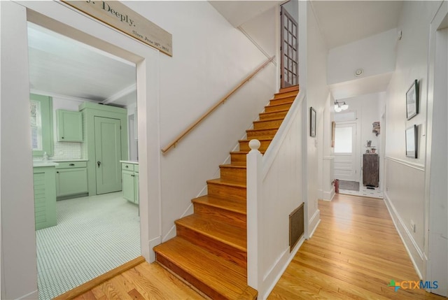 stairway with visible vents, baseboards, and wood finished floors