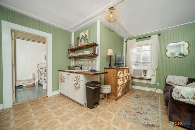 kitchen with lofted ceiling, open shelves, cooling unit, white cabinets, and baseboards