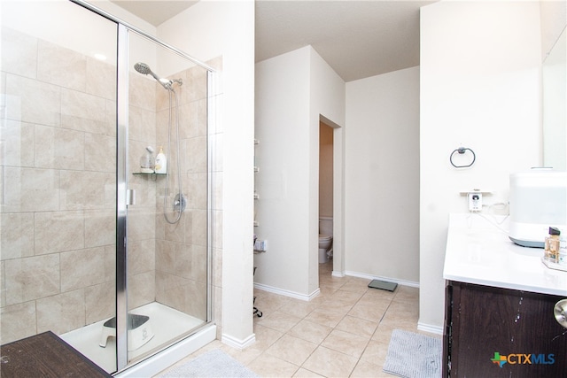 bathroom featuring vanity, walk in shower, tile patterned floors, and toilet