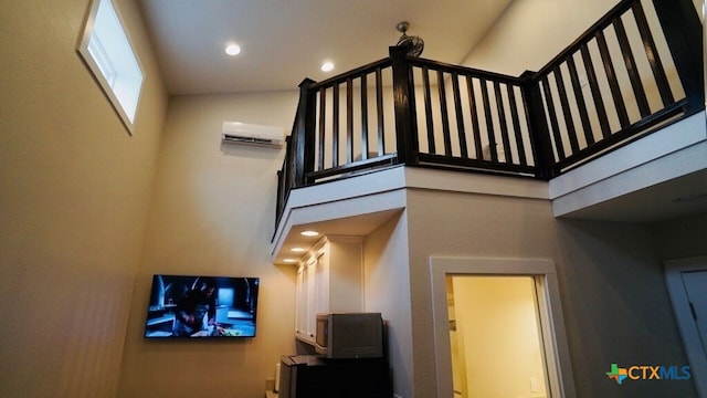 stairs featuring a towering ceiling and a wall unit AC