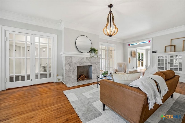 610 N 7th St, Temple, TX 76501 - living area with wood finished floors, crown molding, a tiled fireplace, and a chandelier