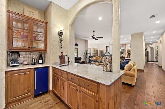 105 Flint Ridge Trl, Georgetown, TX 78628 - indoor wet bar with arched walkways, fridge, light wood finished floors, decorative backsplash, and a ceiling fan