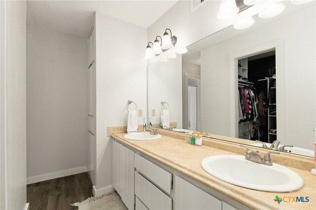 402 Teakwood Dr, Victoria, TX 77901 - full bathroom featuring double vanity, wood finished floors, a walk in closet, and baseboards