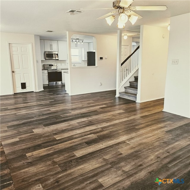 unfurnished living room featuring dark wood-type flooring and ceiling fan