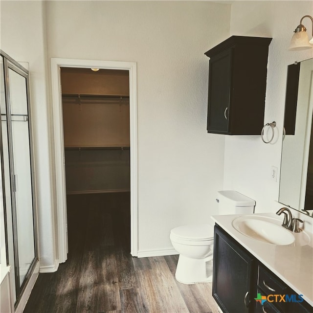 bathroom featuring walk in shower, vanity, hardwood / wood-style floors, and toilet