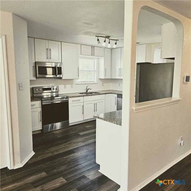 kitchen featuring white cabinetry, appliances with stainless steel finishes, a textured ceiling, dark hardwood / wood-style flooring, and sink