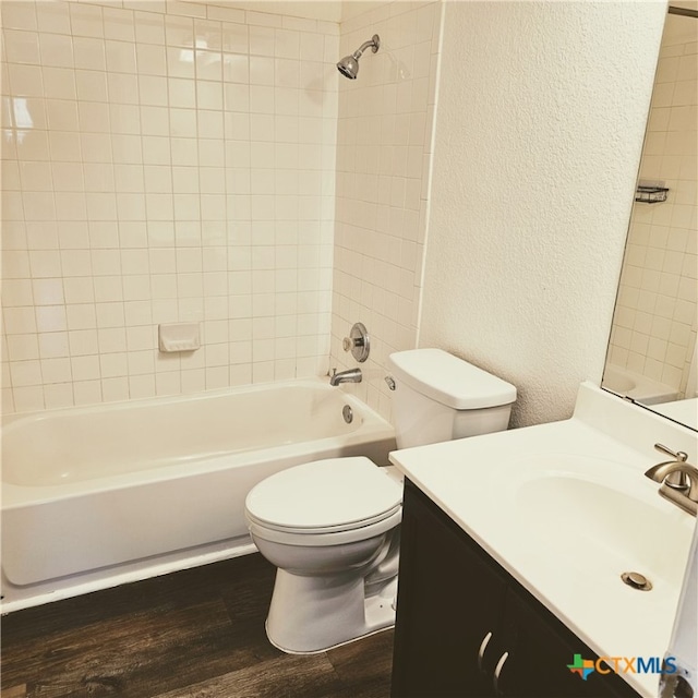 full bathroom with toilet, vanity, tiled shower / bath, and hardwood / wood-style flooring