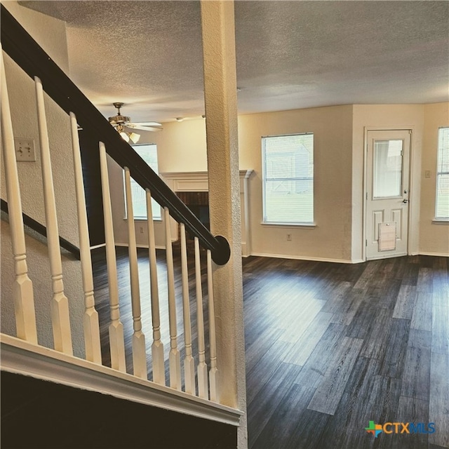 stairway featuring wood-type flooring, a textured ceiling, and ceiling fan