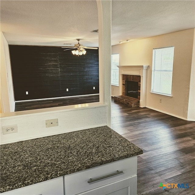 interior space with ceiling fan, wood-type flooring, a textured ceiling, and a brick fireplace