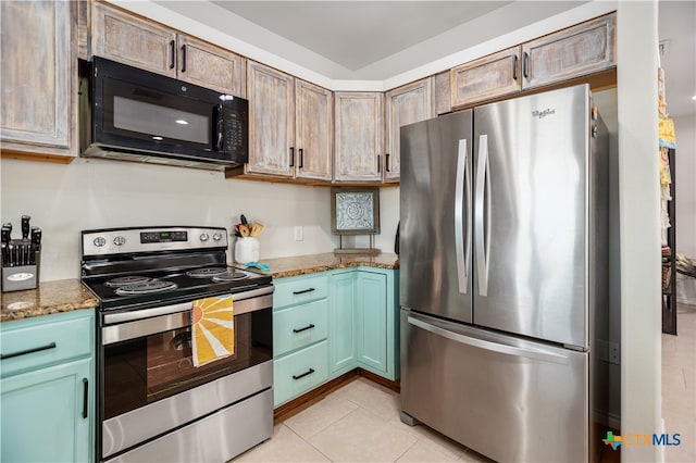 kitchen with appliances with stainless steel finishes, green cabinets, light stone counters, and light tile patterned floors