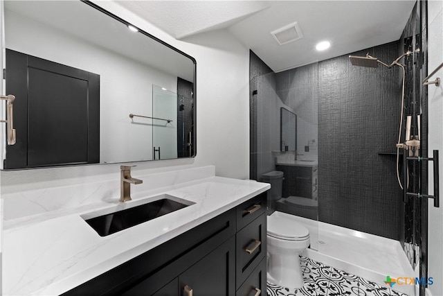 bathroom with visible vents, a tile shower, vanity, tile patterned floors, and toilet