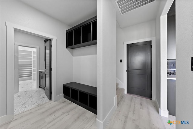 mudroom with baseboards, light wood-style flooring, and visible vents