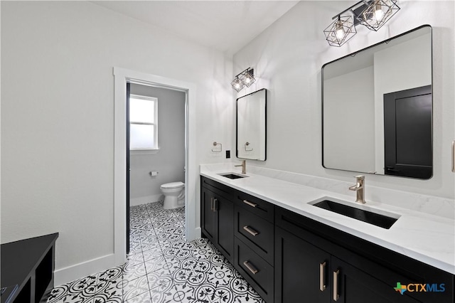 bathroom featuring baseboards, a sink, tile patterned floors, and toilet