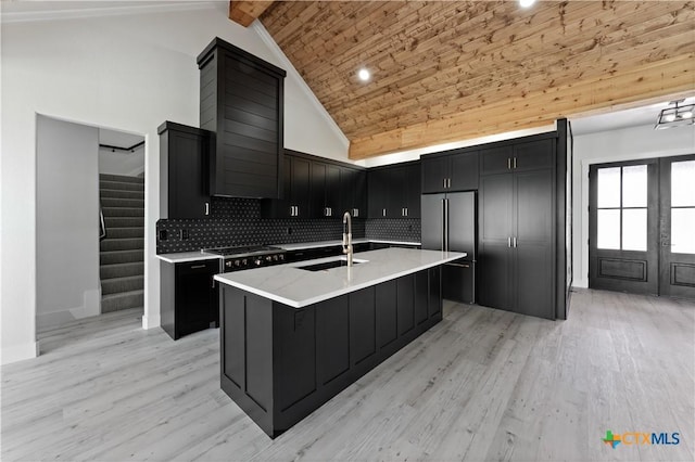 kitchen with dark cabinetry, high vaulted ceiling, a sink, and high quality fridge