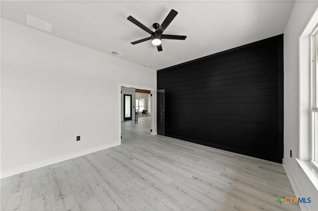 empty room featuring baseboards, ceiling fan, light wood finished floors, and visible vents