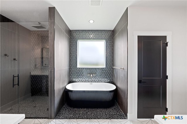 full bathroom featuring a freestanding bath, tile patterned floors, tile walls, visible vents, and a stall shower
